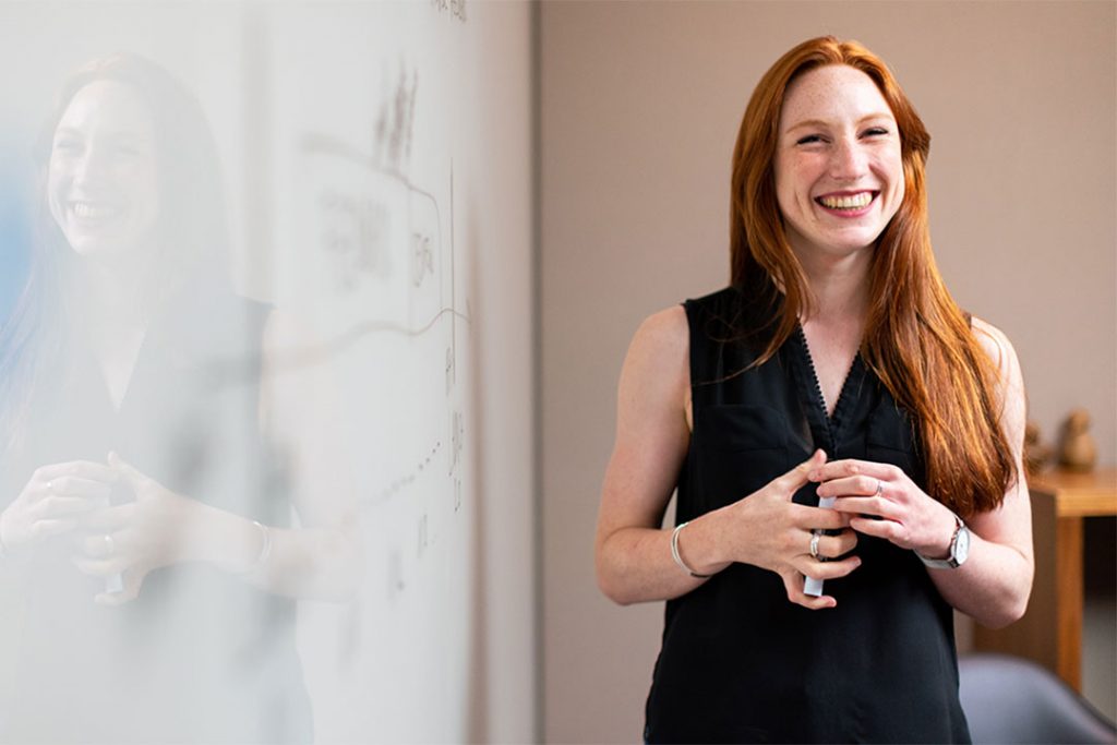 Happy teacher stood next to wipe board